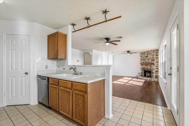 kitchen featuring light tile patterned flooring, sink, stainless steel dishwasher, and a textured ceiling