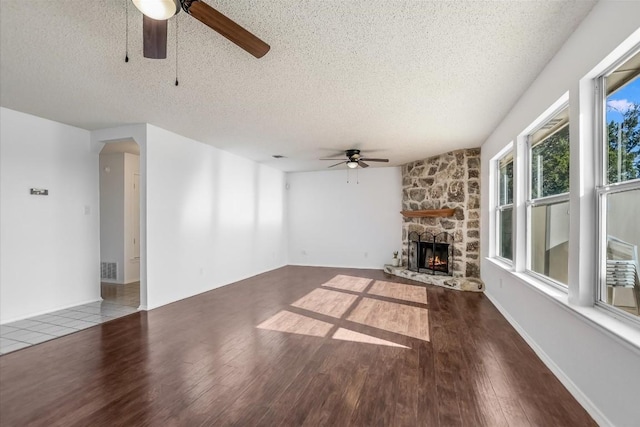 unfurnished living room featuring a fireplace, wood-type flooring, a textured ceiling, and ceiling fan