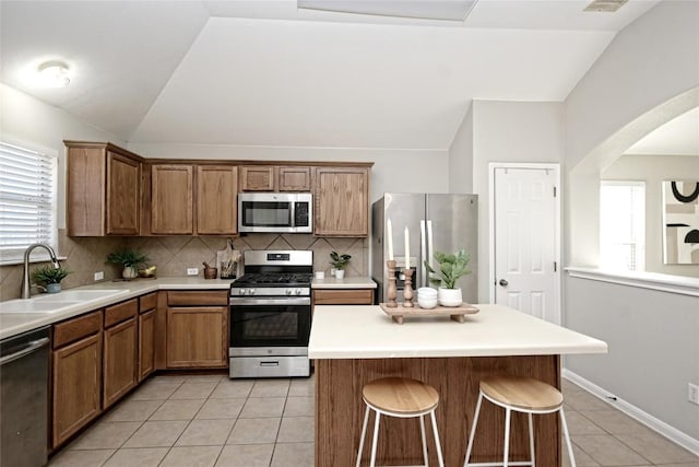 kitchen with appliances with stainless steel finishes, sink, light tile patterned floors, and lofted ceiling