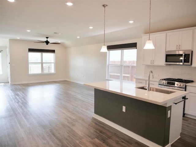 kitchen featuring pendant lighting, appliances with stainless steel finishes, a kitchen island with sink, and white cabinets