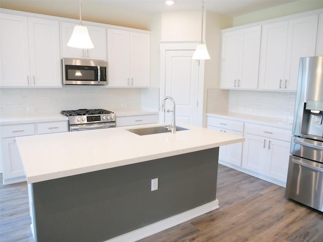 kitchen featuring sink, white cabinetry, appliances with stainless steel finishes, an island with sink, and pendant lighting