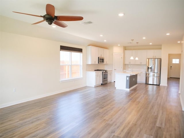 unfurnished living room with ceiling fan, wood-type flooring, and sink