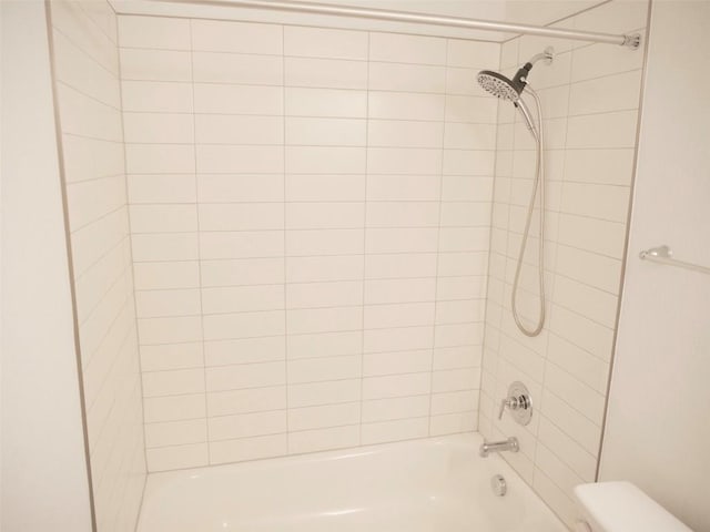 bathroom with tiled shower / bath combo and toilet