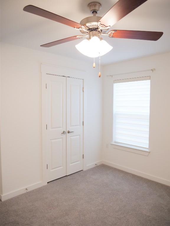 unfurnished bedroom with ceiling fan, carpet floors, and a closet