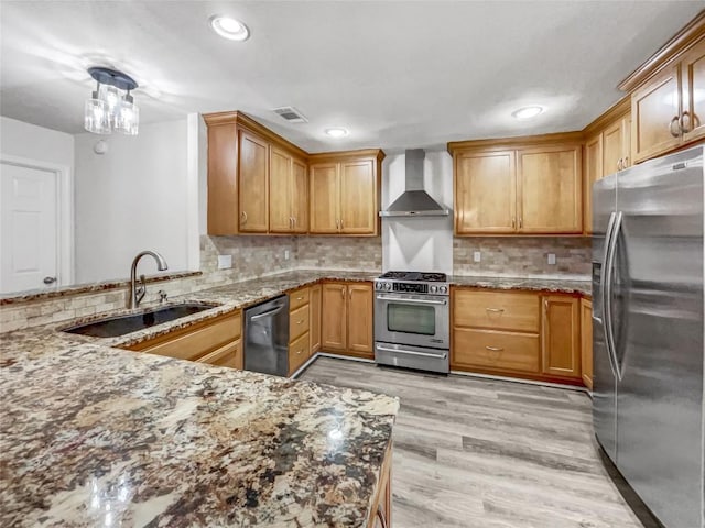 kitchen with sink, light hardwood / wood-style flooring, appliances with stainless steel finishes, kitchen peninsula, and wall chimney range hood