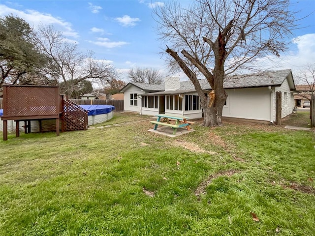 back of house featuring a lawn, a sunroom, and a swimming pool side deck