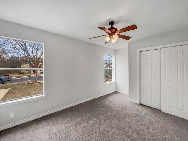 unfurnished bedroom featuring dark carpet, ceiling fan, and a closet