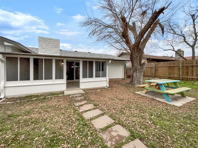 rear view of house featuring a patio area, a sunroom, and a lawn