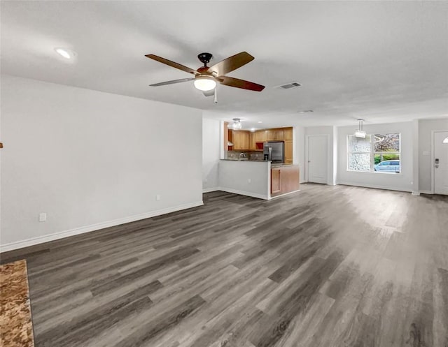 unfurnished living room featuring dark wood-type flooring and ceiling fan