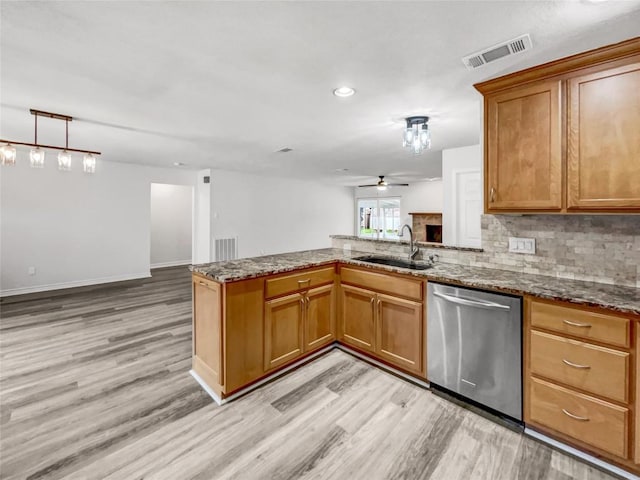 kitchen with stone countertops, sink, stainless steel dishwasher, kitchen peninsula, and light wood-type flooring