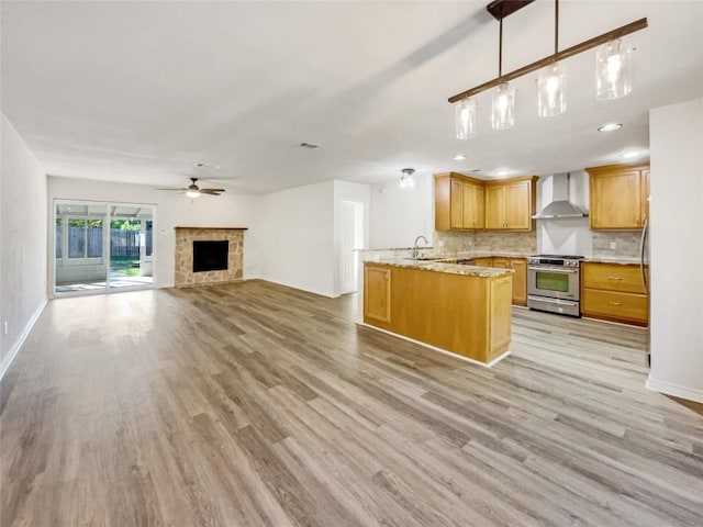 8222 Kearsarge Dr, Austin, TX 78745 - kitchen featuring stainless steel range, wall chimney range hood, open floor plan, light wood finished floors, and recessed lighting