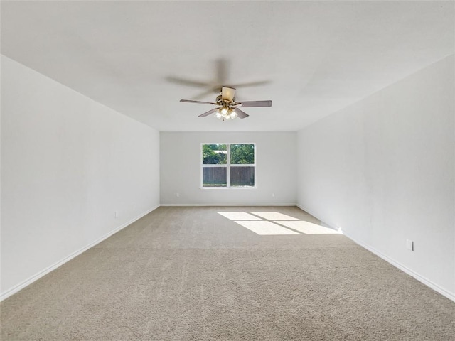 spare room featuring ceiling fan, light colored carpet, and baseboards