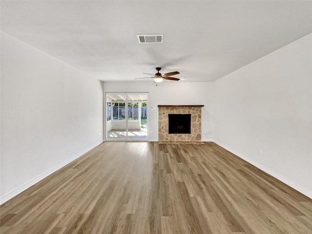 unfurnished living room featuring a ceiling fan, wood finished floors, baseboards, and a fireplace