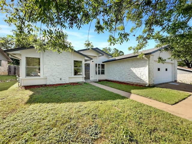 single story home with stone siding, a front yard, an attached garage, and driveway