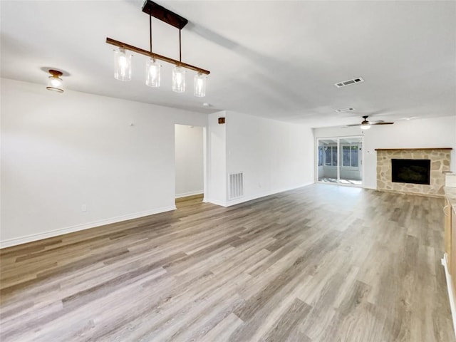 8222 Kearsarge Dr, Austin, TX 78745 - unfurnished living room featuring a stone fireplace, a ceiling fan, light wood-type flooring, and baseboards