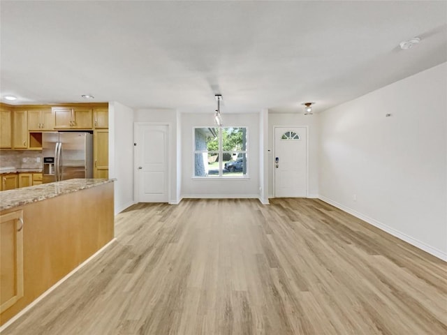 unfurnished living room with baseboards and light wood-type flooring