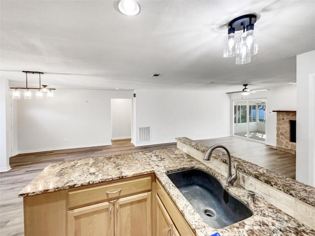 8222 Kearsarge Dr, Austin, TX 78745 - kitchen featuring open floor plan, a sink, light brown cabinetry, light wood-style flooring, and light stone countertops