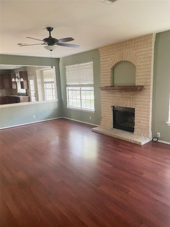 unfurnished living room with ceiling fan, dark wood-type flooring, and a fireplace