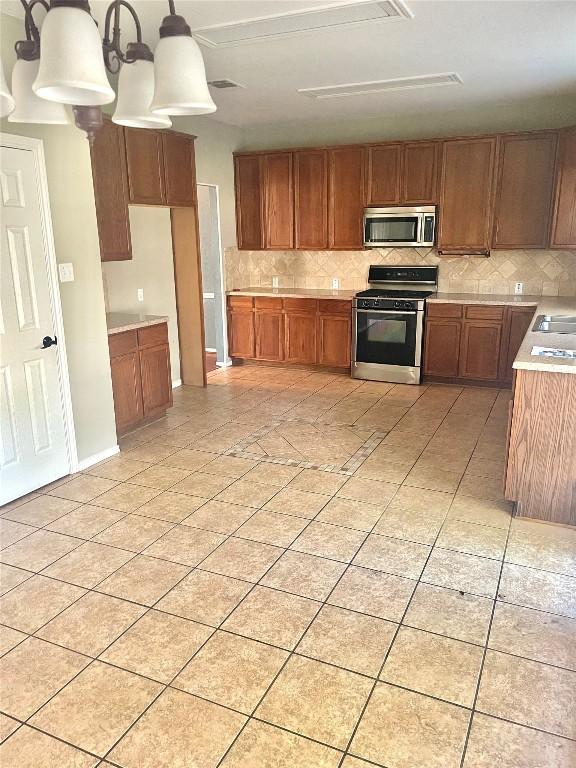 kitchen with light tile patterned floors, decorative light fixtures, stainless steel appliances, and sink