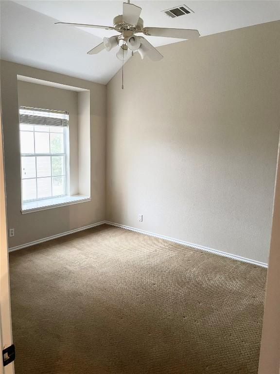 spare room featuring lofted ceiling, carpet flooring, and ceiling fan