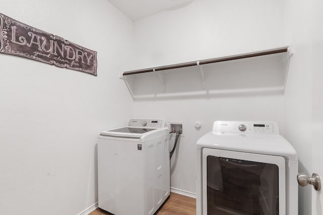 clothes washing area with wood-type flooring and separate washer and dryer