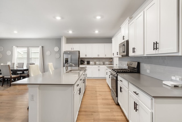 kitchen featuring stainless steel appliances, sink, a center island with sink, and white cabinets