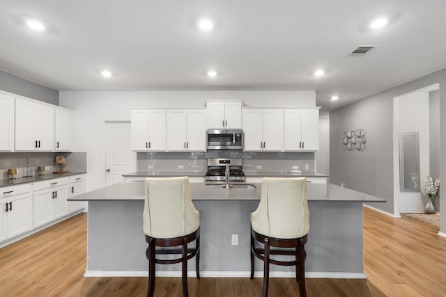 kitchen featuring white cabinetry, appliances with stainless steel finishes, and a kitchen island with sink