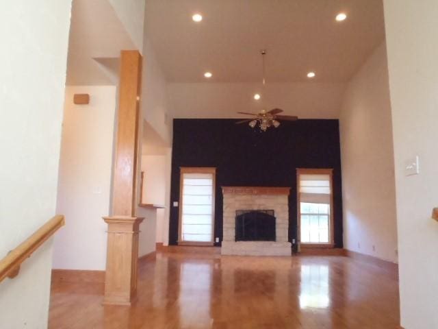 unfurnished living room with a fireplace, decorative columns, and ceiling fan