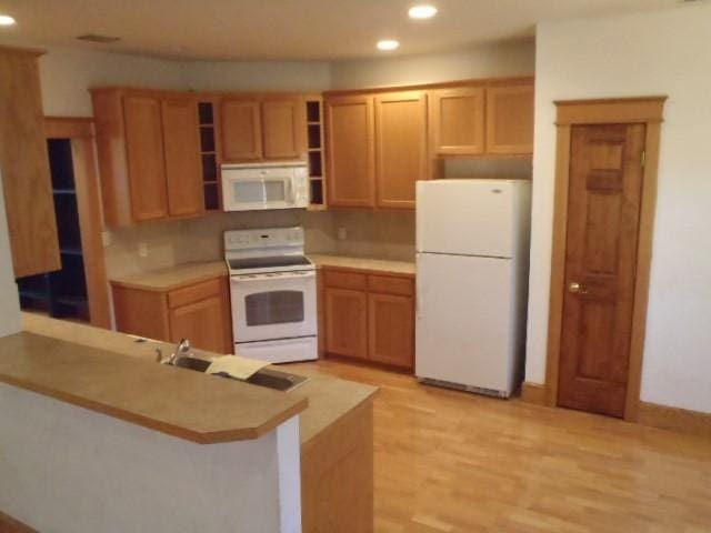 kitchen featuring light wood-type flooring, white appliances, and kitchen peninsula