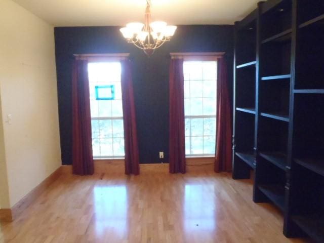 unfurnished room featuring a healthy amount of sunlight, a chandelier, and hardwood / wood-style floors