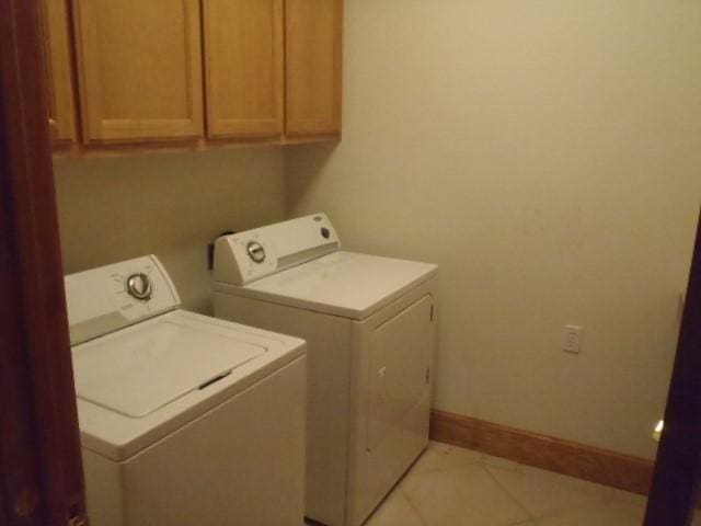 laundry room with cabinets, light tile patterned floors, and washing machine and clothes dryer