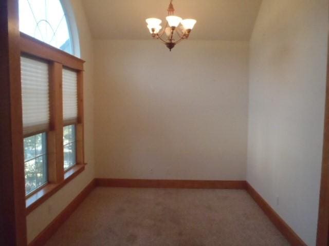 unfurnished room with carpet and a chandelier