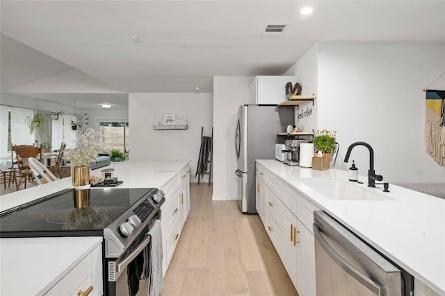 kitchen featuring stainless steel appliances, sink, and white cabinets