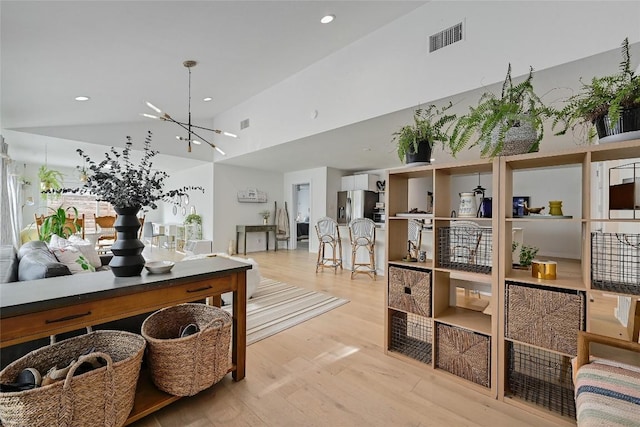 interior space with lofted ceiling, a chandelier, and light wood-type flooring