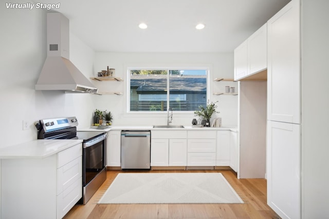 kitchen featuring island range hood, white cabinetry, sink, stainless steel appliances, and light hardwood / wood-style flooring