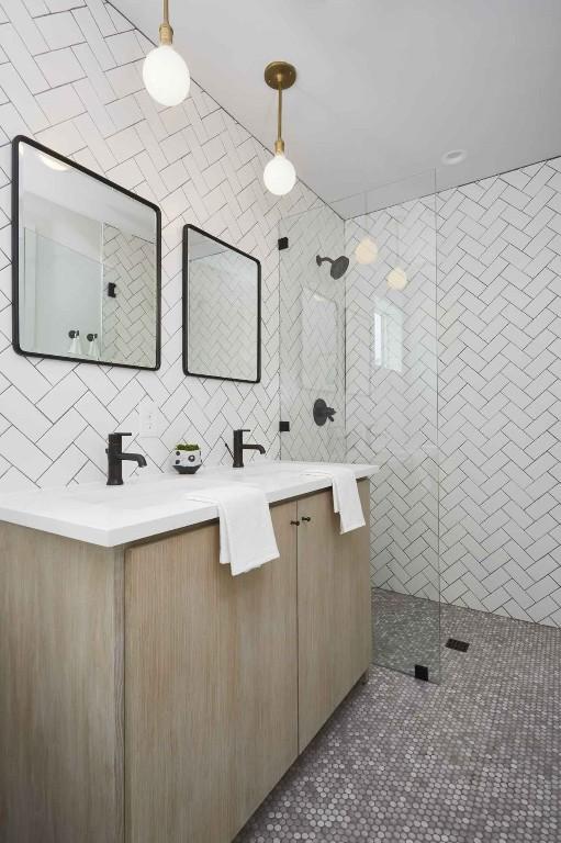 bathroom with vanity, tiled shower, tile walls, and tile patterned floors