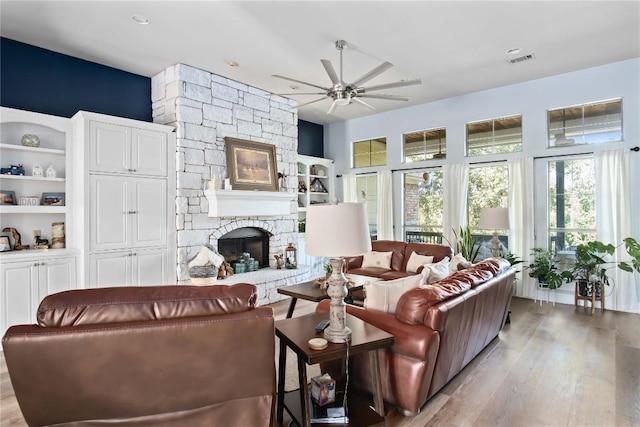 living room with a fireplace, built in features, light hardwood / wood-style floors, and ceiling fan