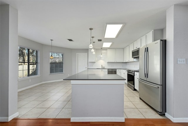 kitchen featuring white cabinetry, stainless steel appliances, a center island, light tile patterned flooring, and decorative light fixtures