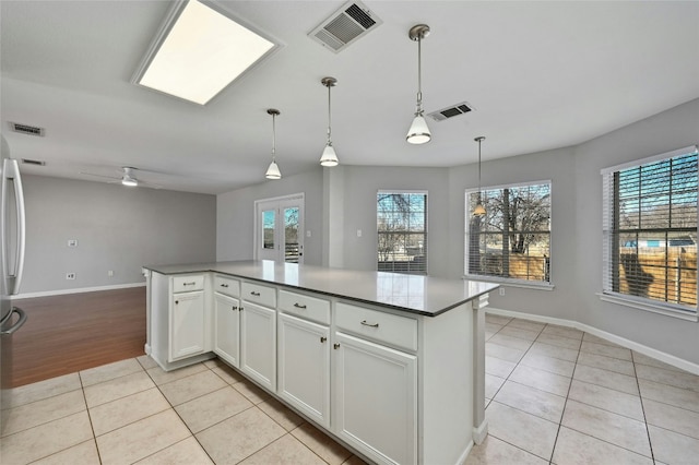 kitchen with ceiling fan, white cabinetry, hanging light fixtures, a center island, and light tile patterned flooring