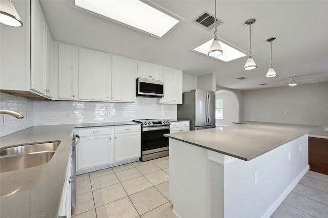 kitchen featuring white cabinetry, tasteful backsplash, light tile patterned floors, appliances with stainless steel finishes, and pendant lighting