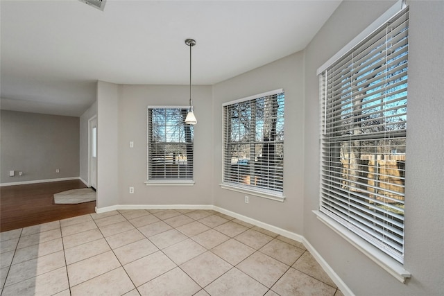 unfurnished dining area featuring light tile patterned floors and baseboards