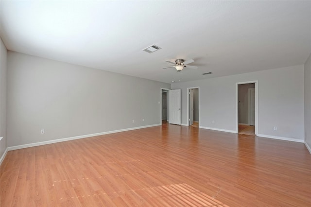 empty room featuring a ceiling fan, light wood-type flooring, visible vents, and baseboards