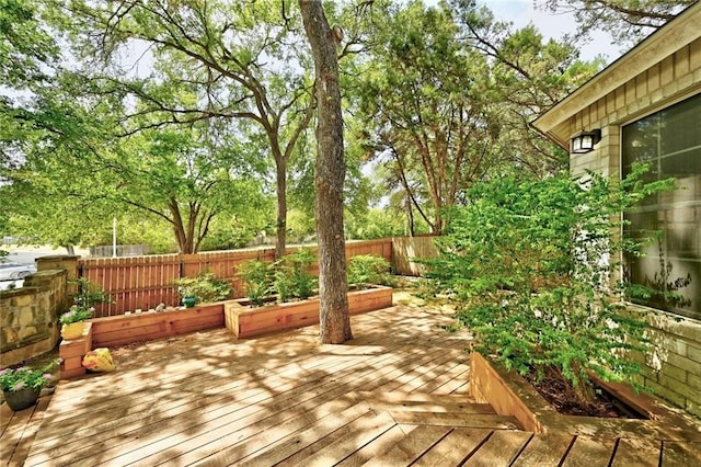 wooden deck with a fenced backyard and a vegetable garden