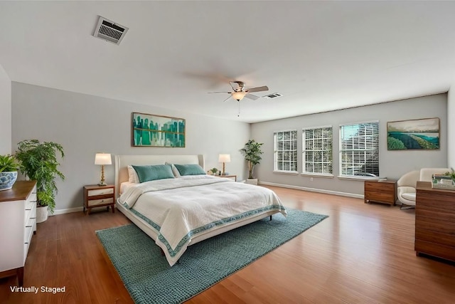 bedroom featuring a ceiling fan, baseboards, visible vents, and wood finished floors