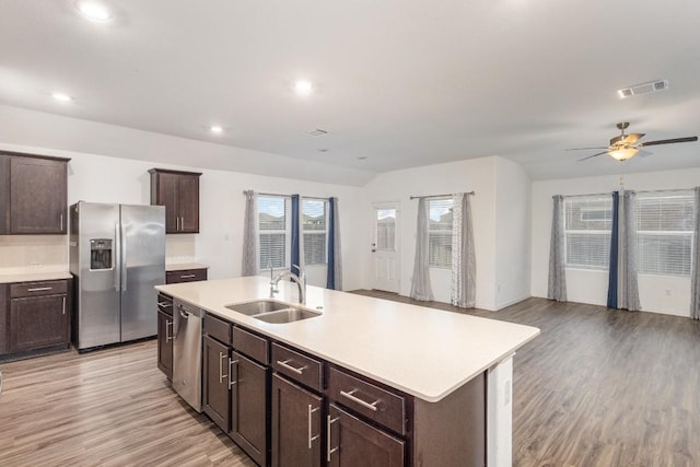 kitchen featuring stainless steel appliances, sink, light hardwood / wood-style floors, and an island with sink