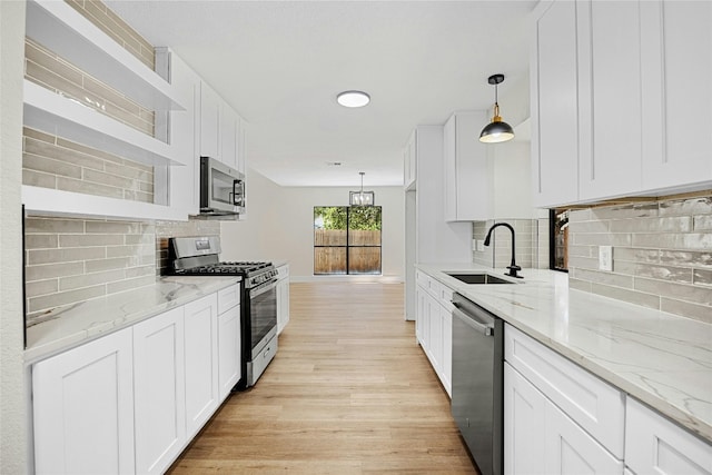 kitchen featuring pendant lighting, appliances with stainless steel finishes, decorative backsplash, and white cabinets