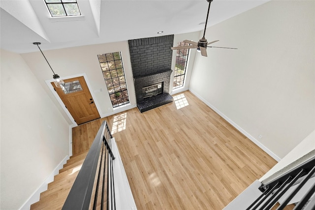 living room with a fireplace, vaulted ceiling, light hardwood / wood-style floors, and a healthy amount of sunlight