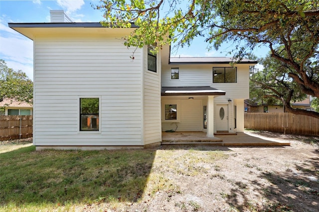 back of property with a lawn and a patio