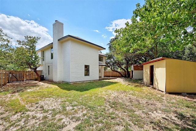 back of house featuring a storage shed and a yard