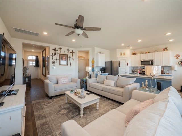 living room featuring sink, dark wood-type flooring, and ceiling fan